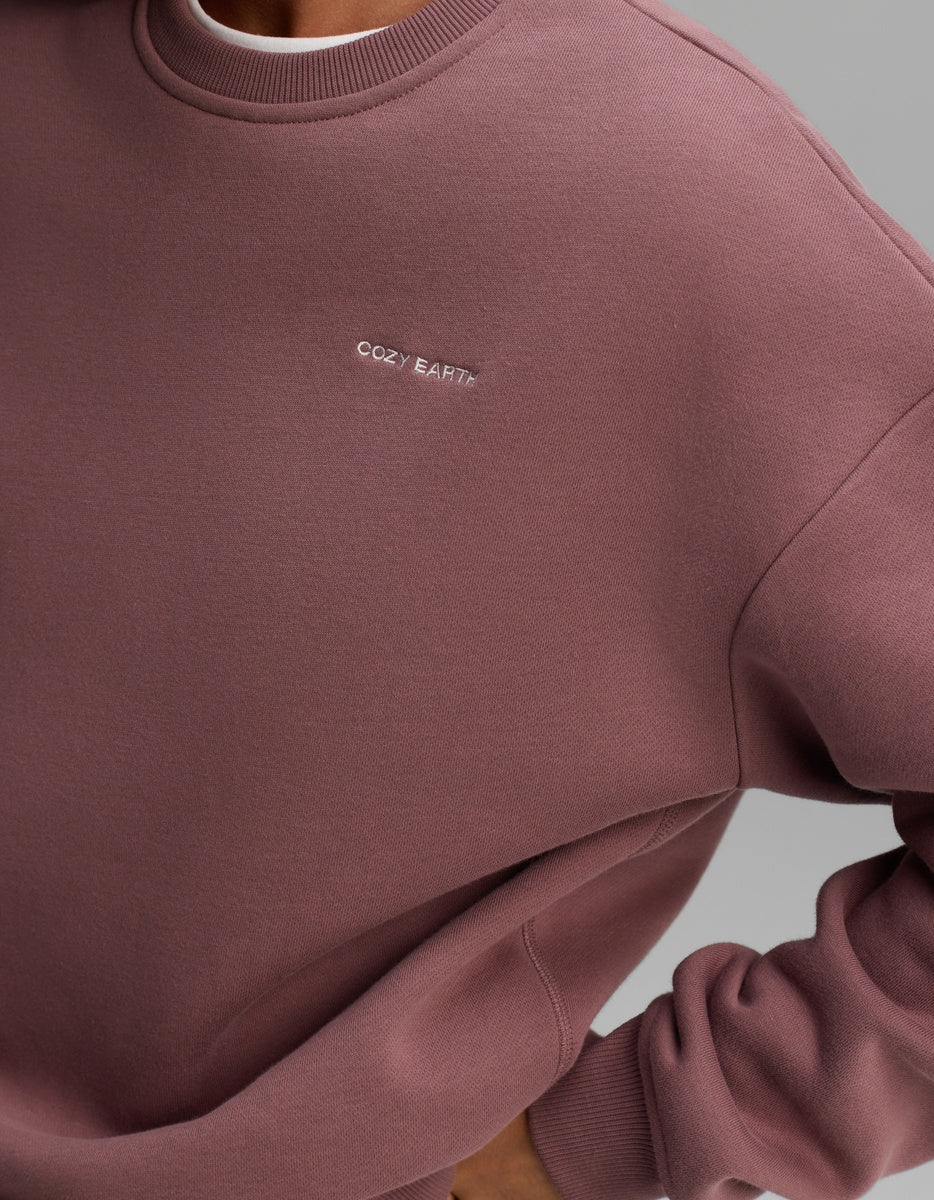 A mauve Women’s CityScape Crewneck sweatshirt with the Cozy Earth brand name embroidered in small white letters on the chest. 