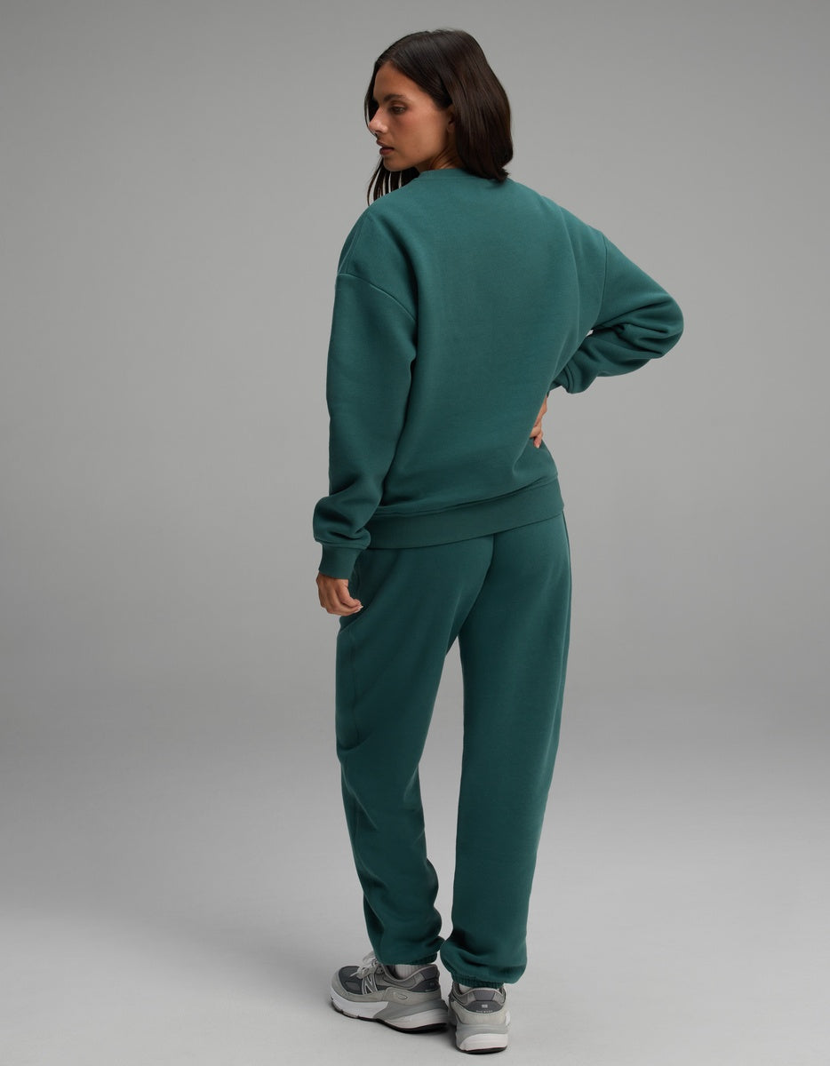 A person wearing a dark green Women’s Cityscape Crewneck & Sweatpant Set.