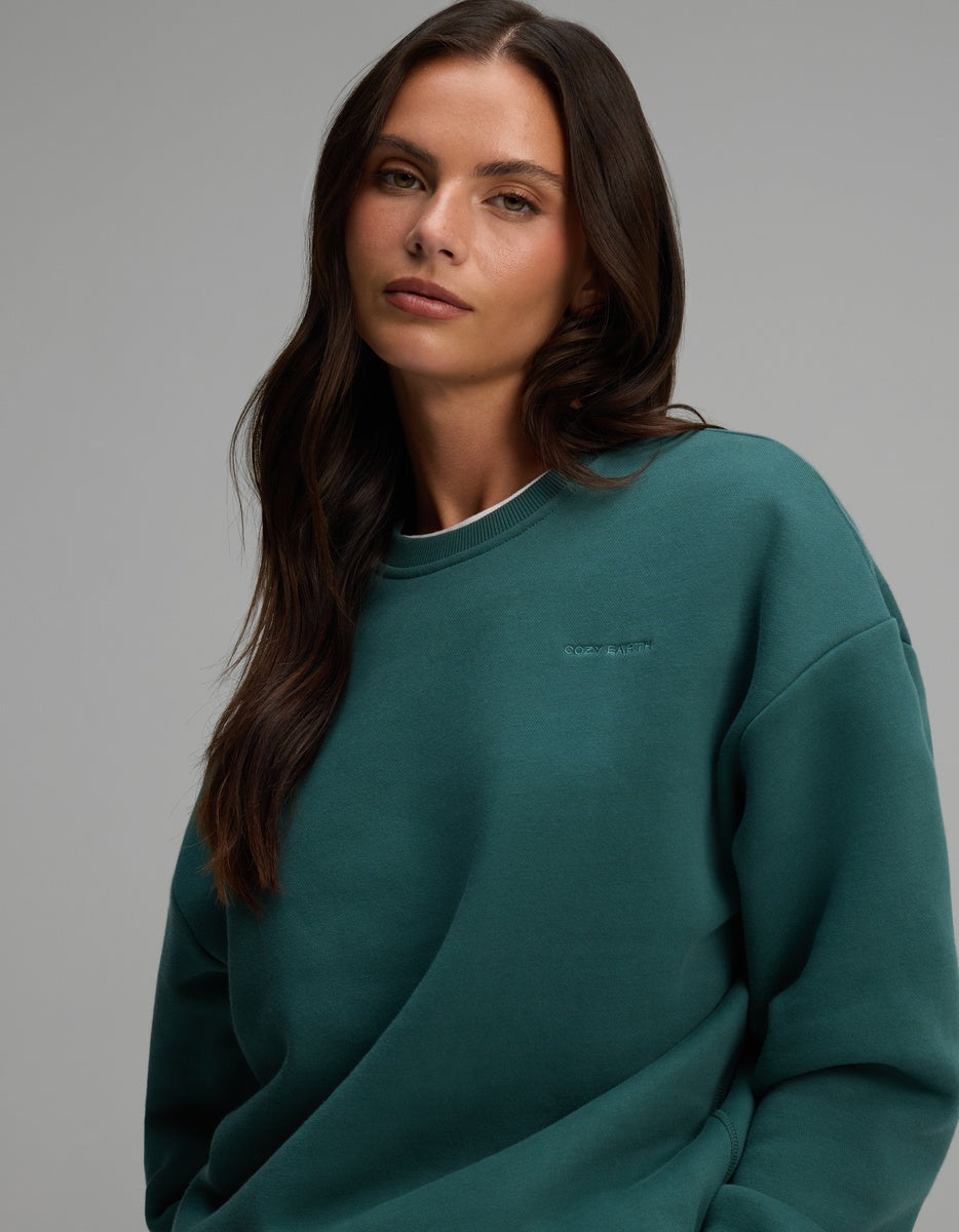 A person wearing a forest green Women’s CityScape Crewneck sweatshirt.