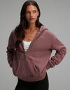 A woman wearing a mauve Cozy Earth Women’s CityScape Full-Zip Hoodie over a white crop top.|Color:Copper Rose