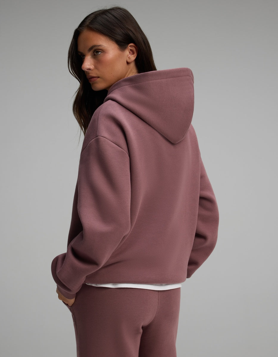A woman wearing a dusty rose Cozy Earth Women’s CityScape Hoodie over a white undershirt.