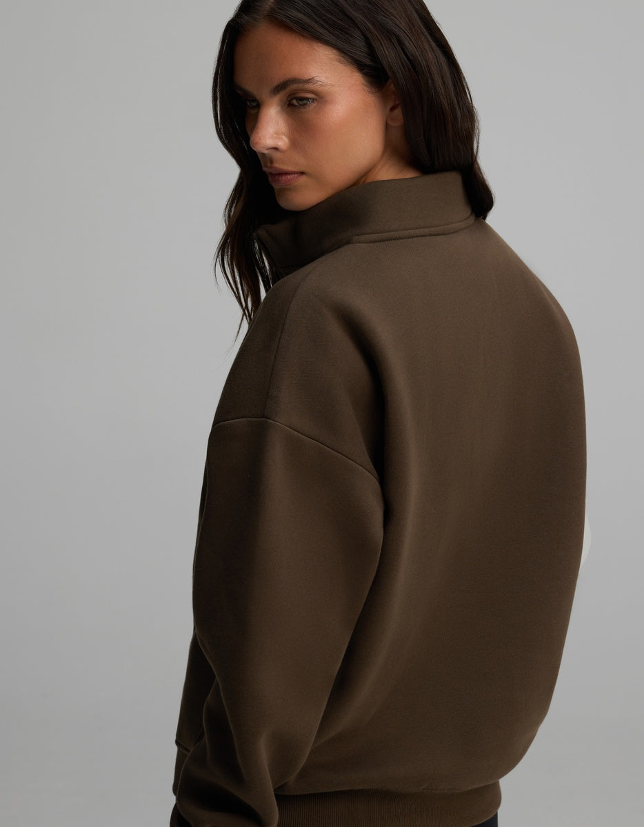 A person viewed from the back and side wearing a brown Cozy Earth Women’s CityScape Quarter Zip with a high collar.