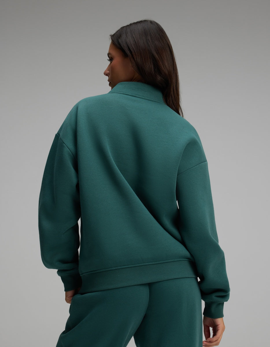 Back view of a person wearing a dark teal Women’s CityScape Quarter Zip sweatshirt with a stand-up collar and matching sweatpants.