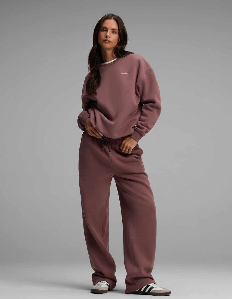 A woman wearing a mauve Cozy Earth Women’s Cityscape Crewneck & Wide Leg Pant Set with sneakers.