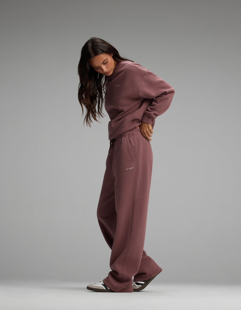 A woman wearing a mauve Cozy Earth Women’s Cityscape Crewneck & Wide Leg Pant Set, consisting of a matching crewneck sweatshirt and wide-leg sweatpants.