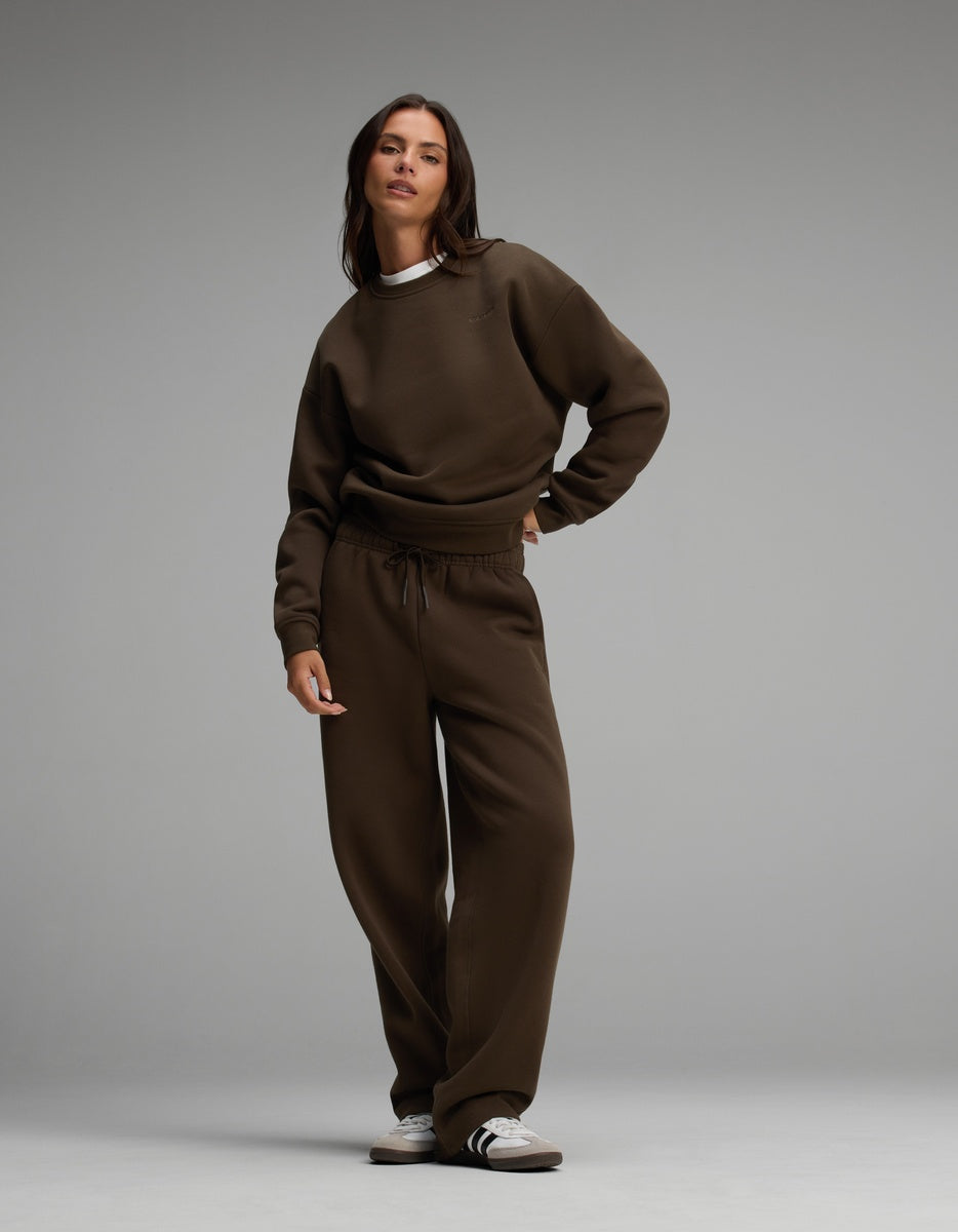 A woman wearing a dark brown Cozy Earth Women’s Cityscape Crewneck & Wide Leg Pant Set with a drawstring waist and white and black sneakers.
