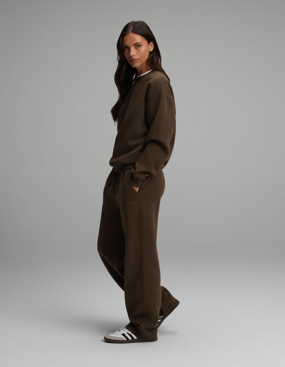 A person wearing a dark brown Cozy Earth Women’s Cityscape Crewneck & Wide Leg Pant Set, paired with white and black sneakers.