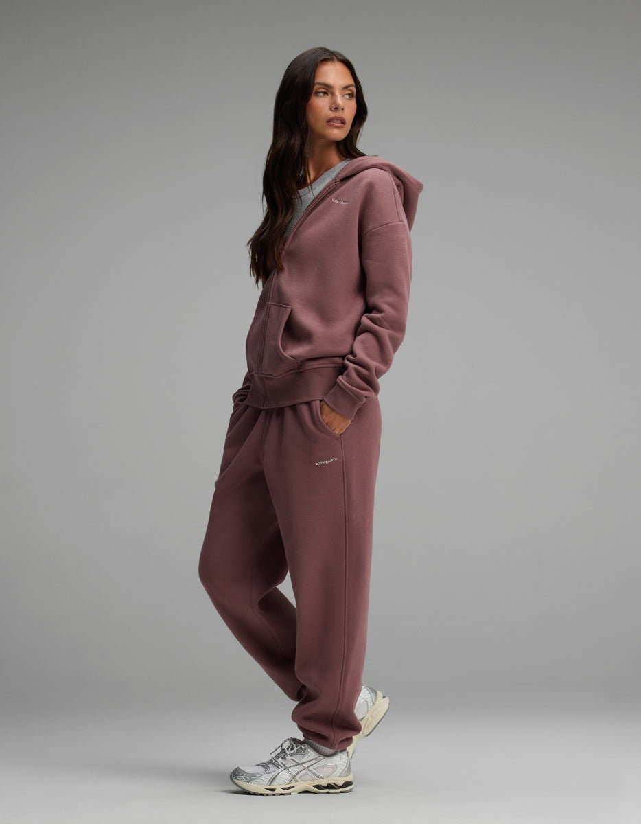 A person wearing a mauve Cozy Earth Women’s Cityscape Full-Zip Hoodie & Sweatpant Set with sneakers.