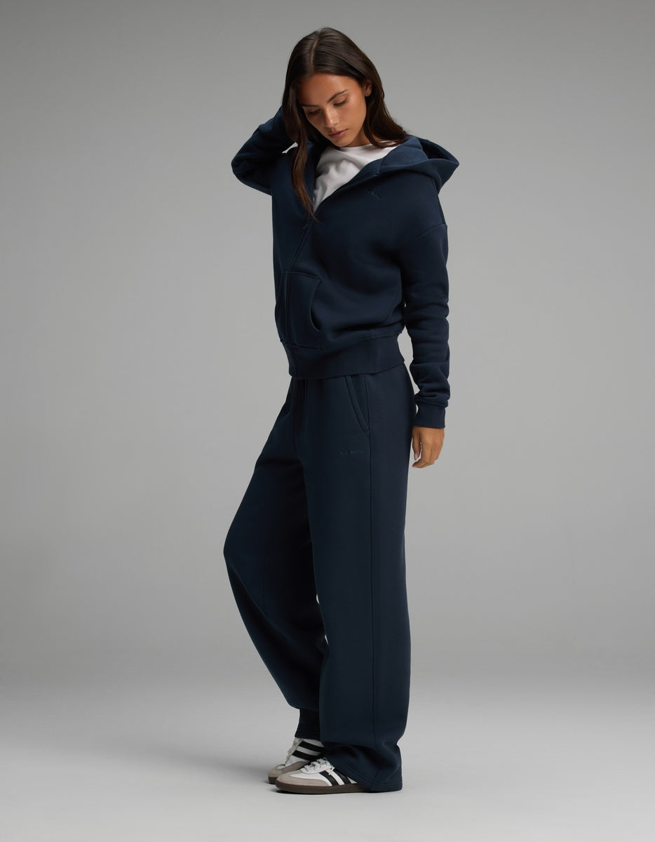 A woman wearing a navy blue Cozy Earth Women’s Cityscape Full-Zip Hoodie & Wide Leg Pant Set over a white shirt.