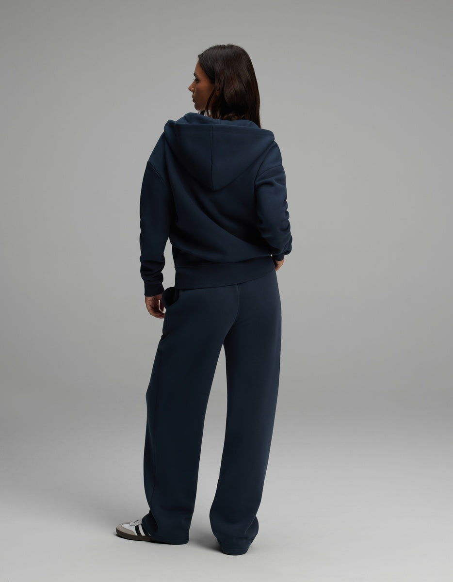 A woman wearing a dark navy Cozy Earth Women’s Cityscape Full-Zip Hoodie & Wide Leg Pant Set, featuring a hooded zip-up sweatshirt and matching wide-leg pants.