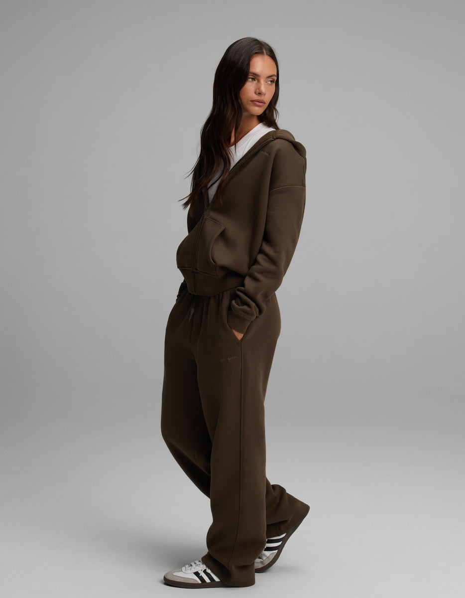 A woman wearing a dark brown Women’s Cityscape Full-Zip Hoodie & Wide Leg Pant Set, featuring a zip-up hoodie and matching wide-leg pants.