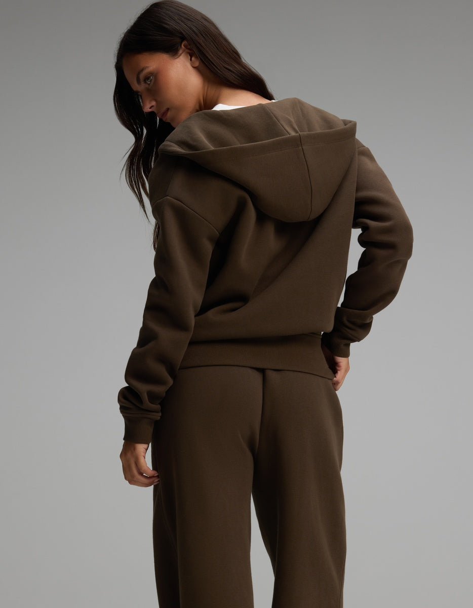 A person wearing a dark brown Cozy Earth Women’s Cityscape Full-Zip Hoodie & Wide Leg Pant Set consisting of a full-zip hooded sweatshirt and matching wide-leg pants.