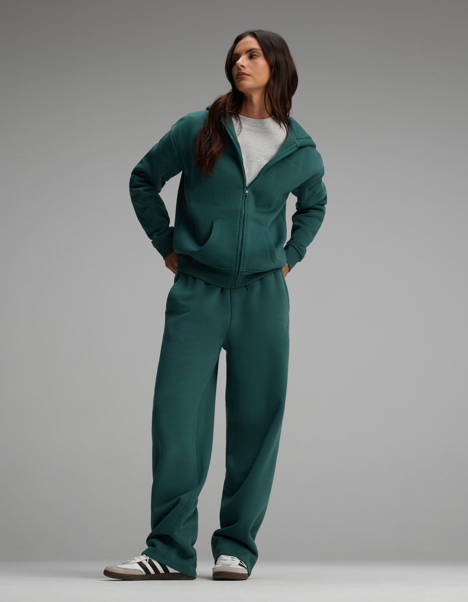 A person wearing the dark green Cozy Earth Women’s Cityscape Full-Zip Hoodie & Wide Leg Pant Set over a grey crew-neck t-shirt.