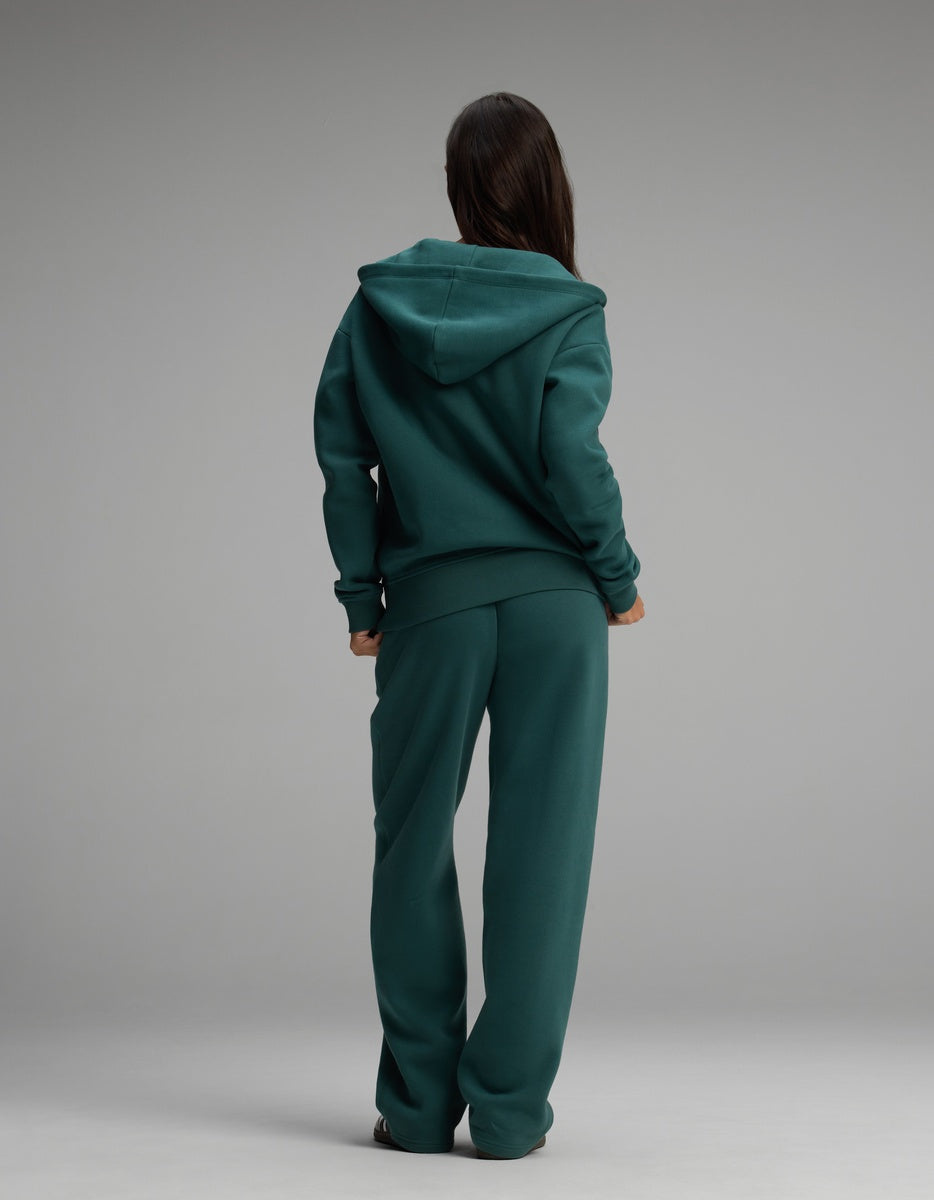 Back view of a person wearing a dark green Women’s Cityscape Full-Zip Hoodie & Wide Leg Pant Set consisting of a full-zip hooded sweatshirt and matching wide-leg lounge pants.