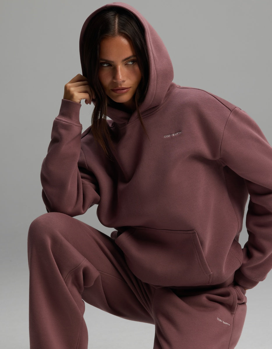 A person wearing a mauve Women’s Cityscape Hoodie & Wide Leg Pant Set consisting of a matching hooded sweatshirt and wide-leg pants.