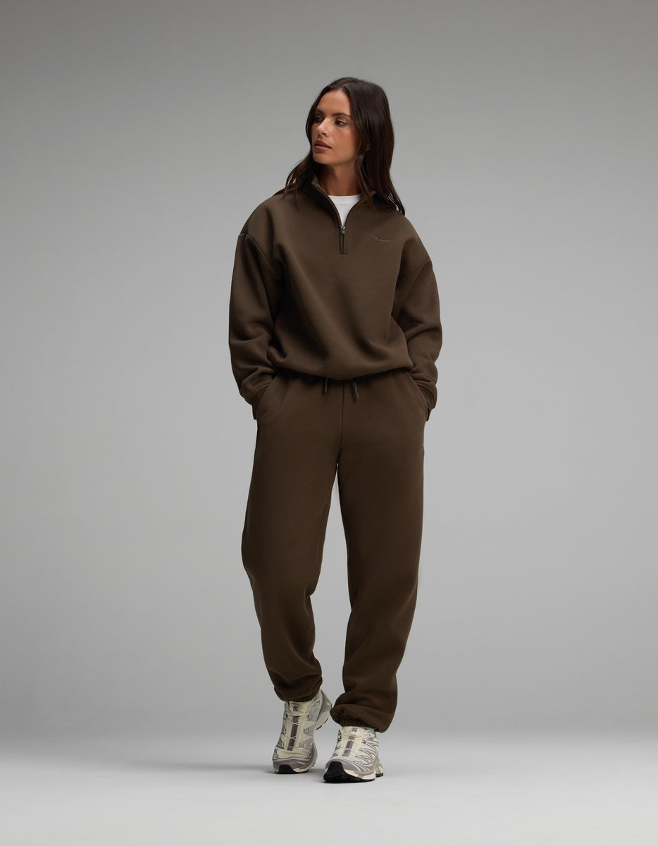 A woman wearing a dark brown Cozy Earth Women’s Cityscape Quarter Zip & Sweatpant Set with athletic sneakers.