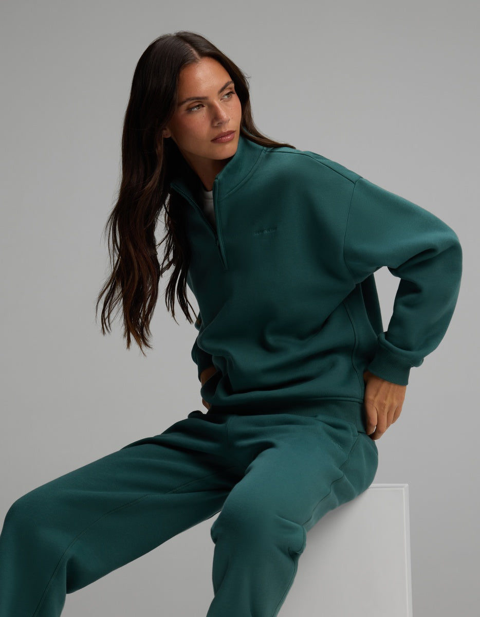 A woman wearing a dark green Women’s Cityscape Quarter Zip & Sweatpant Set.