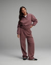 A person wearing a dusty rose Cozy Earth Women’s Cityscape Quarter Zip & Wide Leg Pant Set, featuring a quarter-zip sweatshirt and matching wide-leg sweatpants with a drawstring waist.|Color:Copper Rose