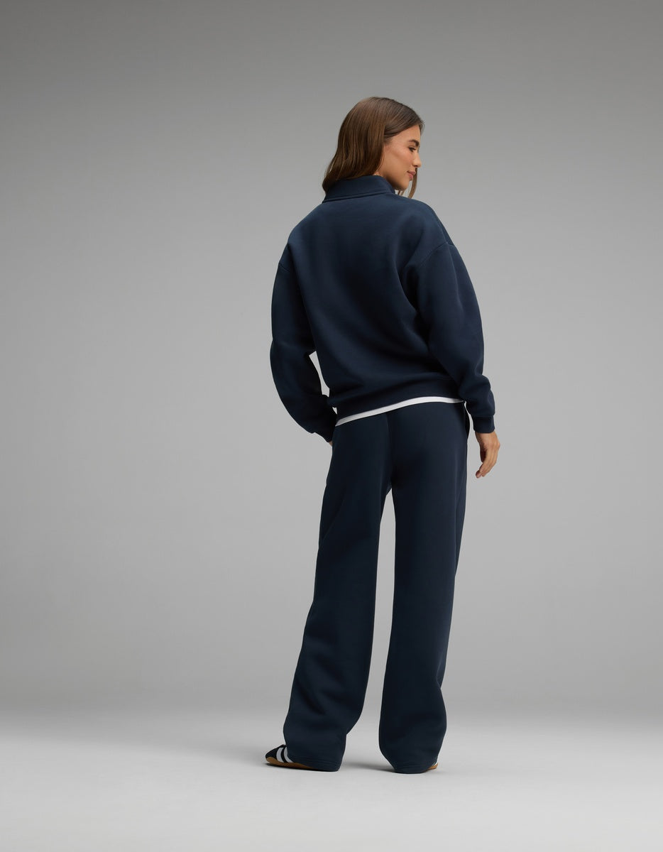 A woman wearing a dark navy blue Cozy Earth Women’s Cityscape Quarter Zip & Wide Leg Pant Set consisting of a quarter-zip sweatshirt and matching wide-leg pants.