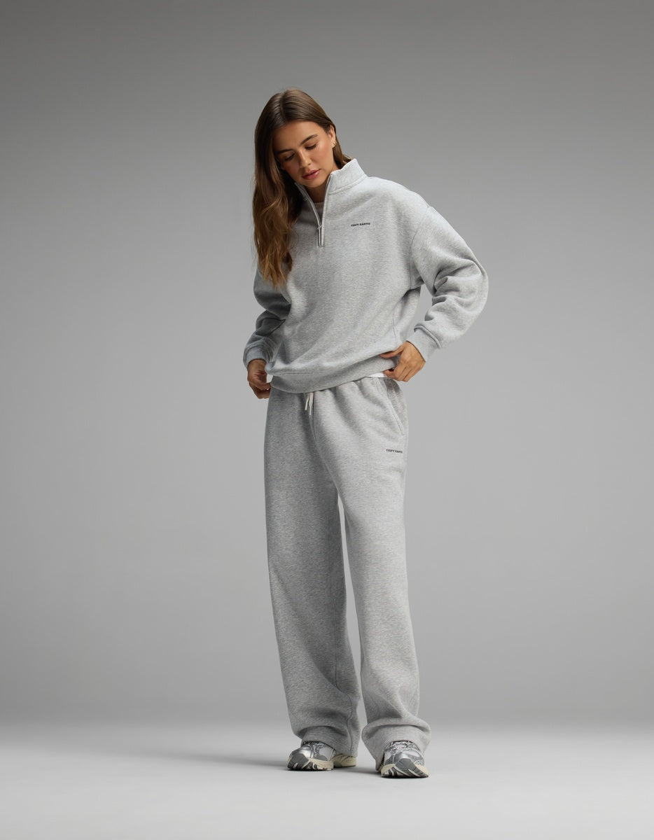 A woman wearing a gray Women’s Cityscape Quarter Zip & Wide Leg Pant Set consisting of a quarter-zip pullover and matching wide-leg sweatpants.