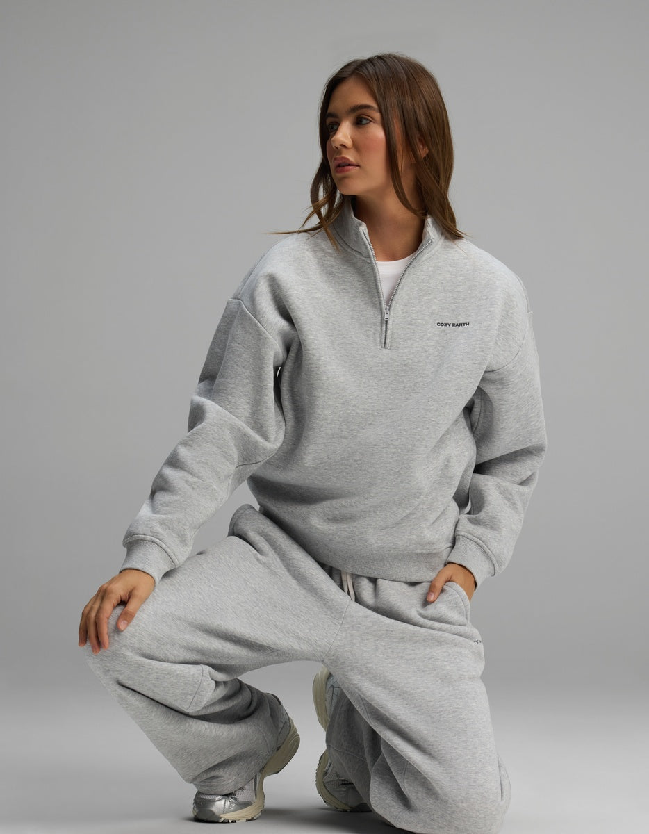 A person wearing a grey Women’s Cityscape Quarter Zip & Wide Leg Pant Set, crouching while looking away from the camera.