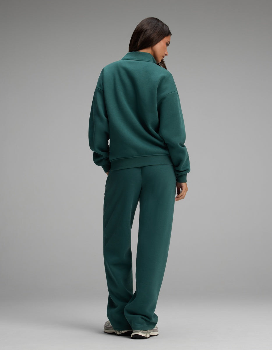 A person seen from behind, wearing the dark green Cozy Earth Women’s Cityscape Quarter Zip & Wide Leg Pant Set consisting of a quarter-zip sweatshirt and matching wide-leg pants.