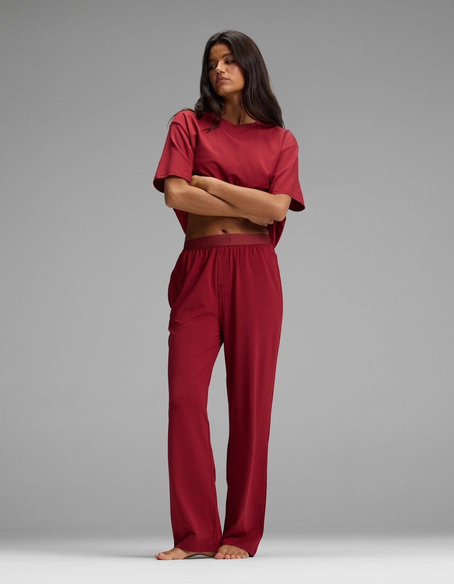 A person wearing a matching dark red short-sleeved top and Cozy Earth Women’s First Layer Pajama Pant with a relaxed fit and elastic waistband.