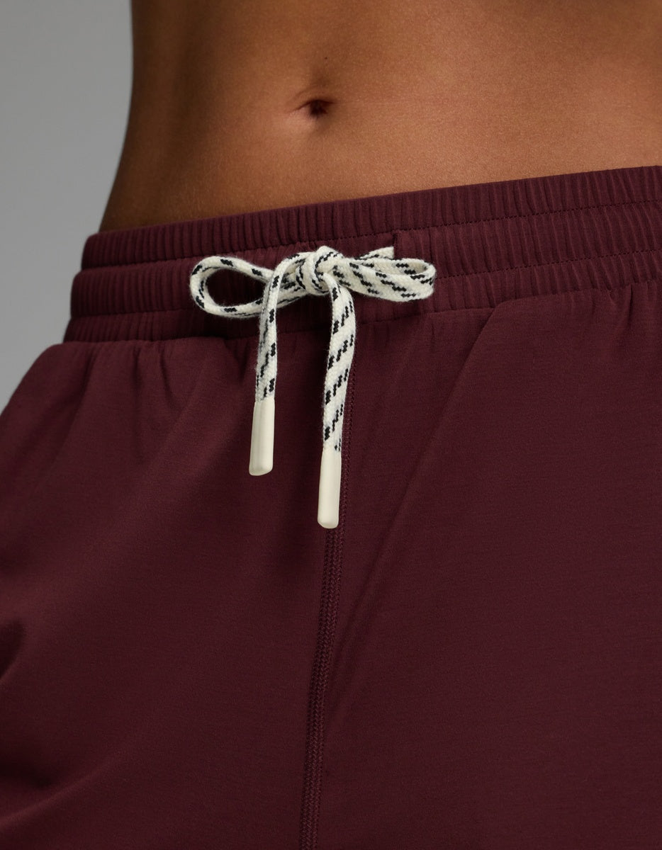 A close-up of a person’s lower torso wearing Cozy Earth Women’s Studio Wide Leg Pant in maroon, featuring a white and black drawstring tied in a bow.
