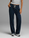 A person wearing Cozy Earth’s Women’s Studio Wide Leg Pant in Eclipse stands with one hand in their pocket against a plain background.|Color:Eclipse