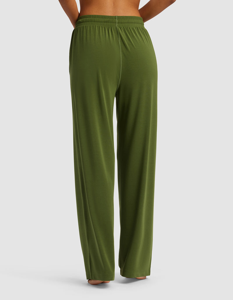 Back view of a person wearing Cozy Earth's Women's Studio Wide Leg Pant in olive green with an elastic waistband, barefoot against a plain light gray background.