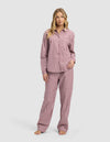 A woman stands barefoot in a Cozy Earth Women's Sutton Long Sleeve Pajama Set, featuring a red and white checkered button-up shirt and loose pants, against a plain light background.|Color:Mulberry Gingham
