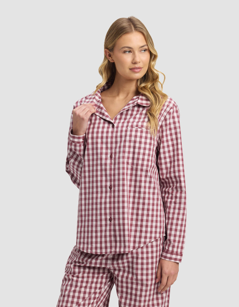 A woman with long blonde hair models the Cozy Earth Women's Sutton Long Sleeve Pajama Top, pink and white plaid, looking relaxed to the side against a light gray background.