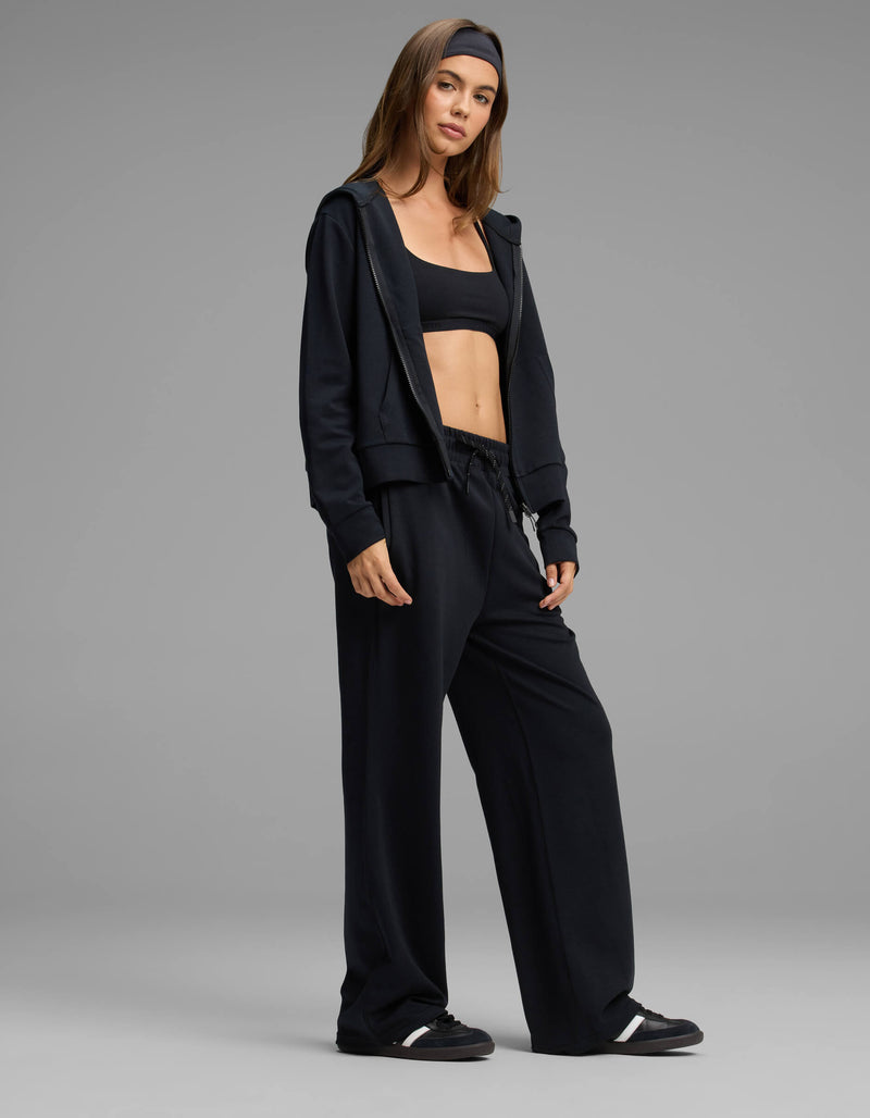A woman stands confidently against a plain gray background, wearing the Cozy Earth Women's Versa Zip-Down Hoodie & Straight Leg Pant Set in black.