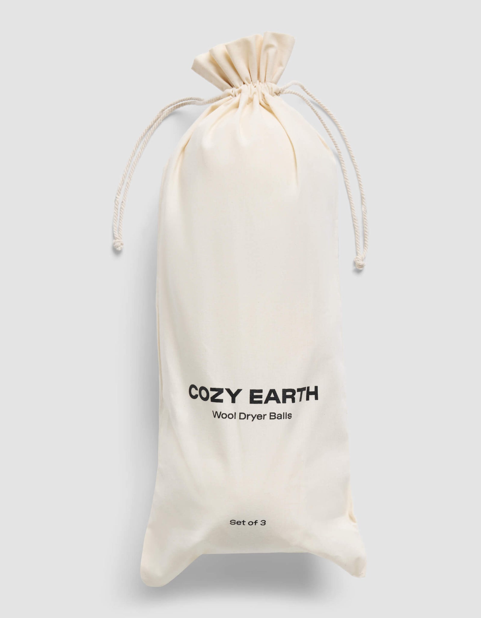 A cream-colored drawstring bag with "Cozy Earth Wool Dryer Balls" and "Set of 3" printed on it is displayed against a plain light gray background.