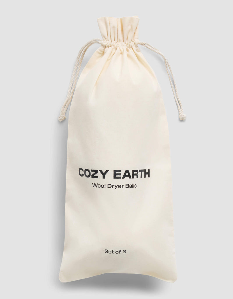 A cream-colored drawstring bag with "Cozy Earth" and "Wool Dryer Balls" printed in black on the front, labeled as a set of 3, is shown against a plain light gray background.