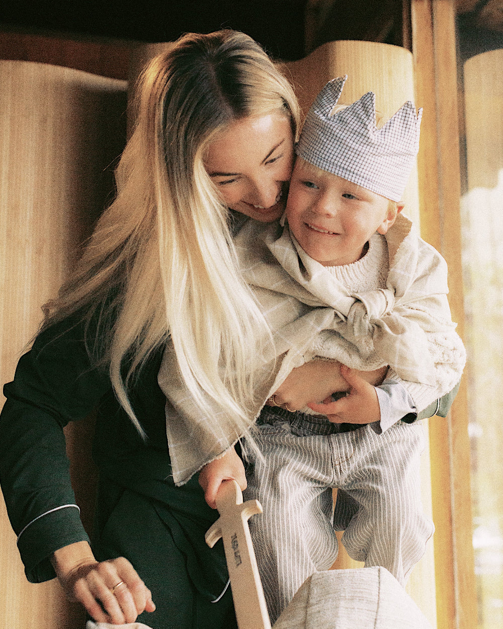 Woman holding a child wearing a crown indoors