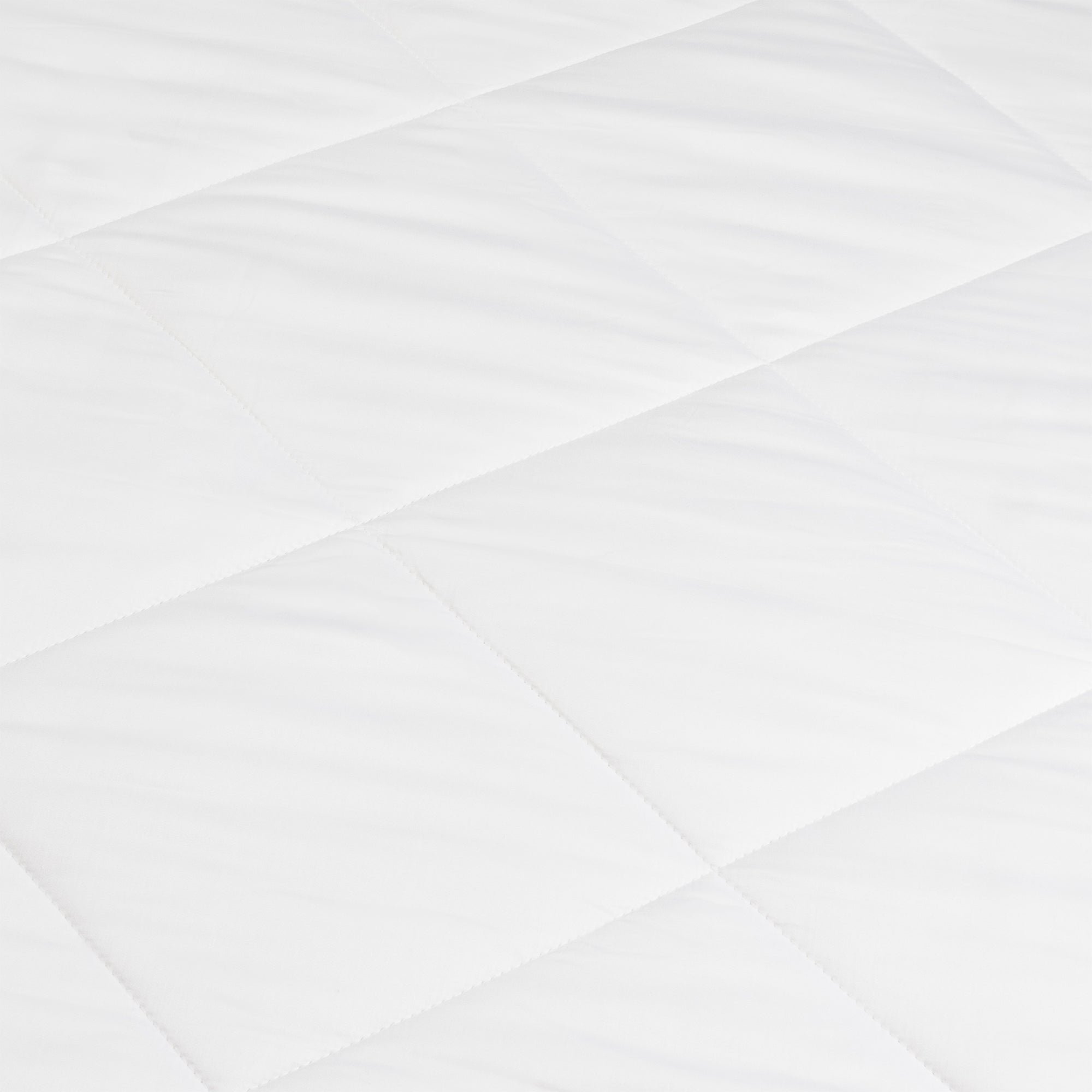 A close-up of the Cozy Earth Bamboo Viscose Comforter shows its smooth, soft white quilted fabric with a diamond pattern formed by intersecting stitched lines.