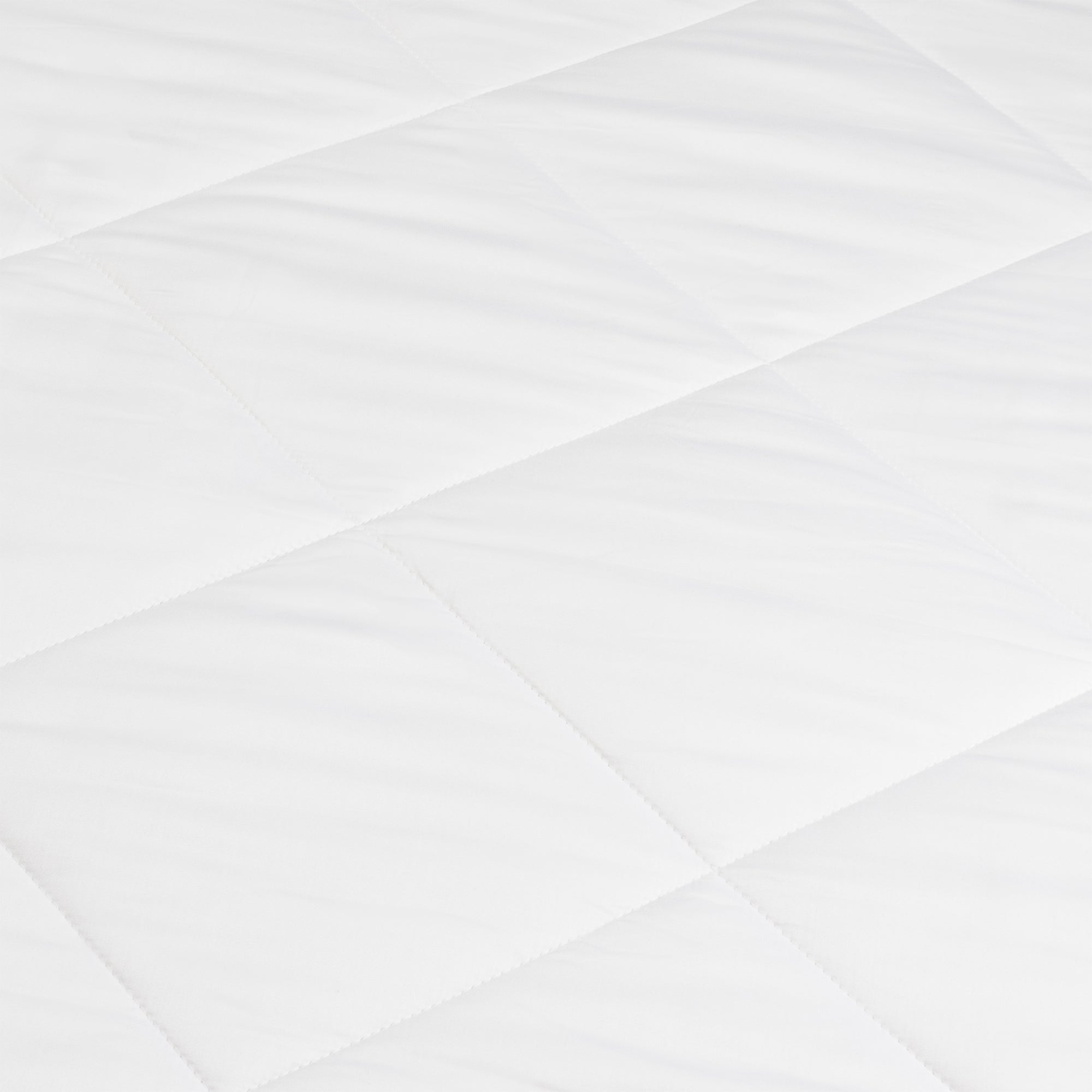 A close-up of the Cozy Earth Bamboo Viscose Comforter shows its smooth, soft white quilted fabric with a diamond pattern formed by intersecting stitched lines.