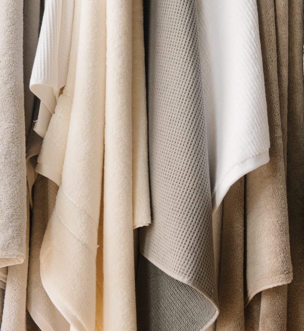 A cllose-up of a variety of Cozy Earth Bath Towels in neutral colors