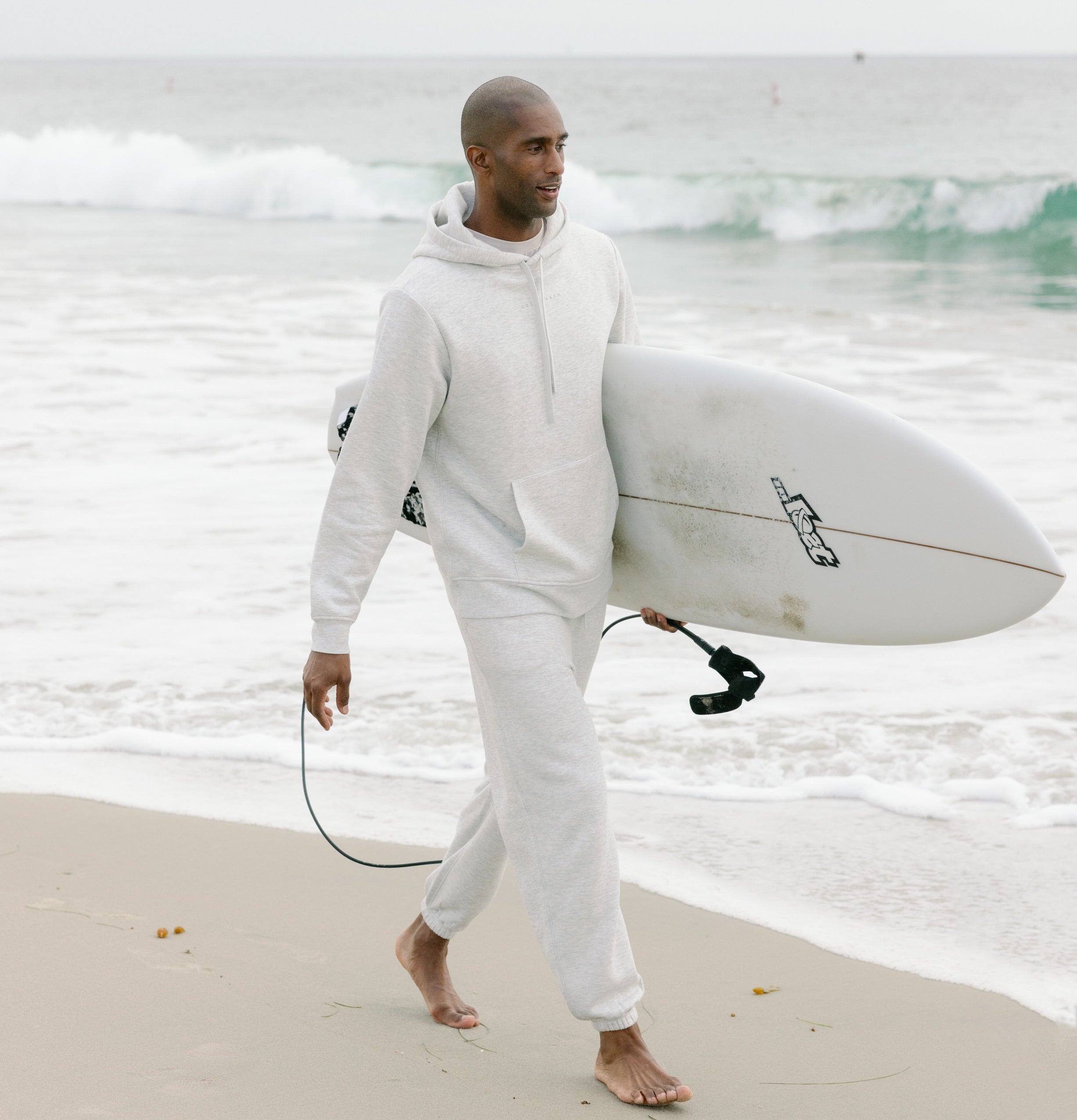 Man carrying surfboard in heather grey cityscape set 