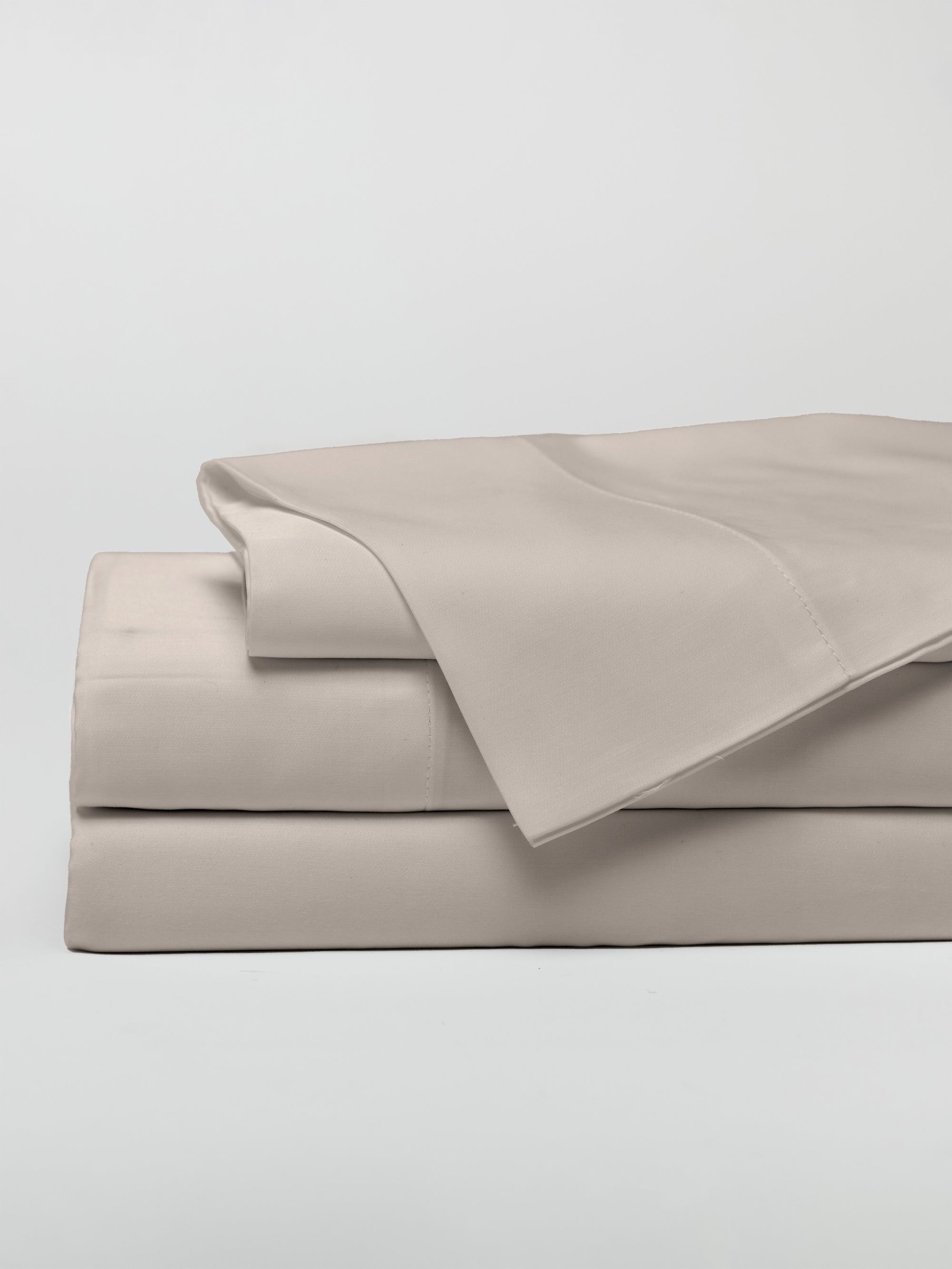 A neatly folded stack of Cozy Earth's Bamboo Sheet Set in Driftwood displayed against a plain white background. The set includes a flat sheet, a fitted sheet, and pillowcases, all meticulously arranged with a smooth and clean appearance.