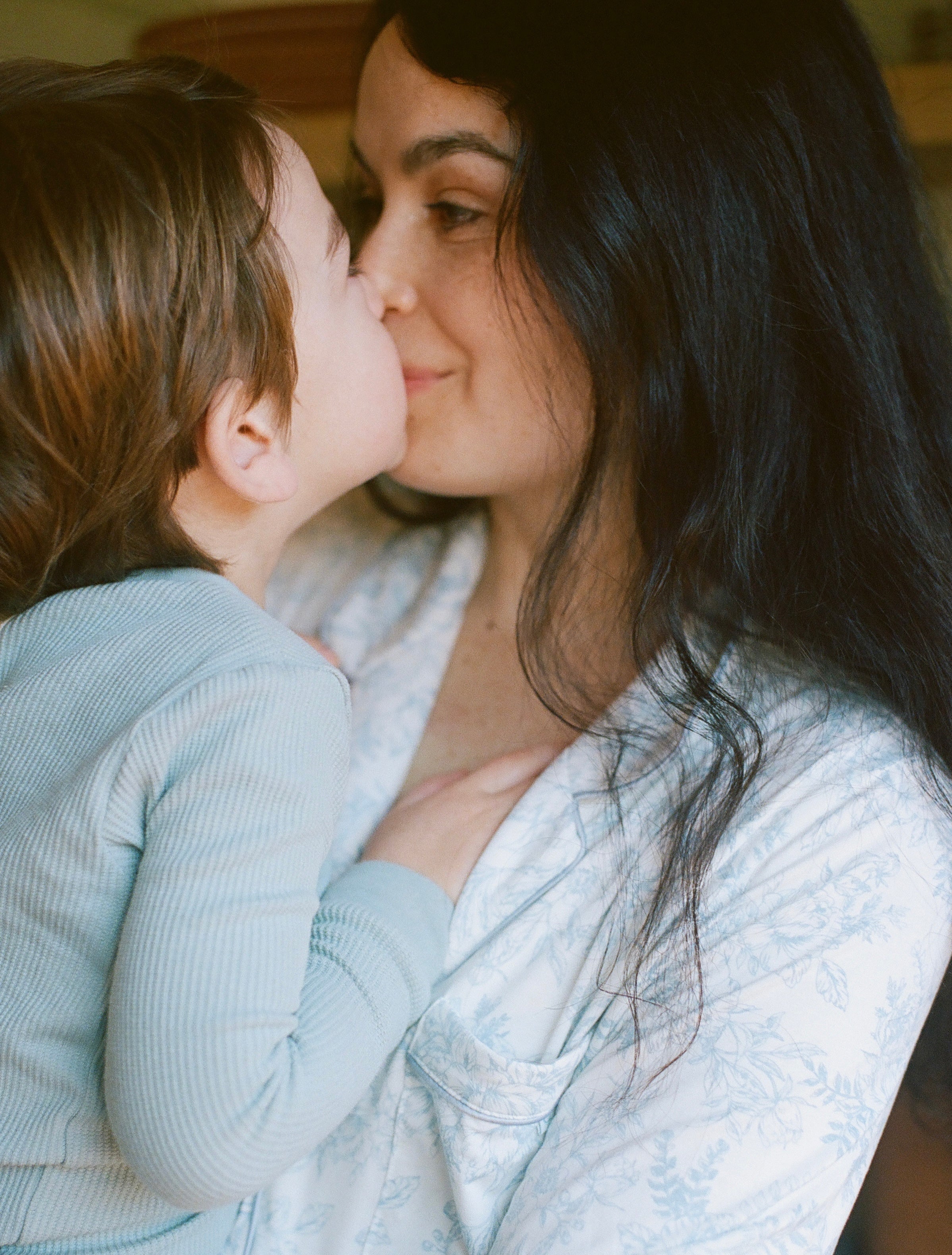 Woman and child sharing a tender moment, with the child kissing the woman on the cheek.