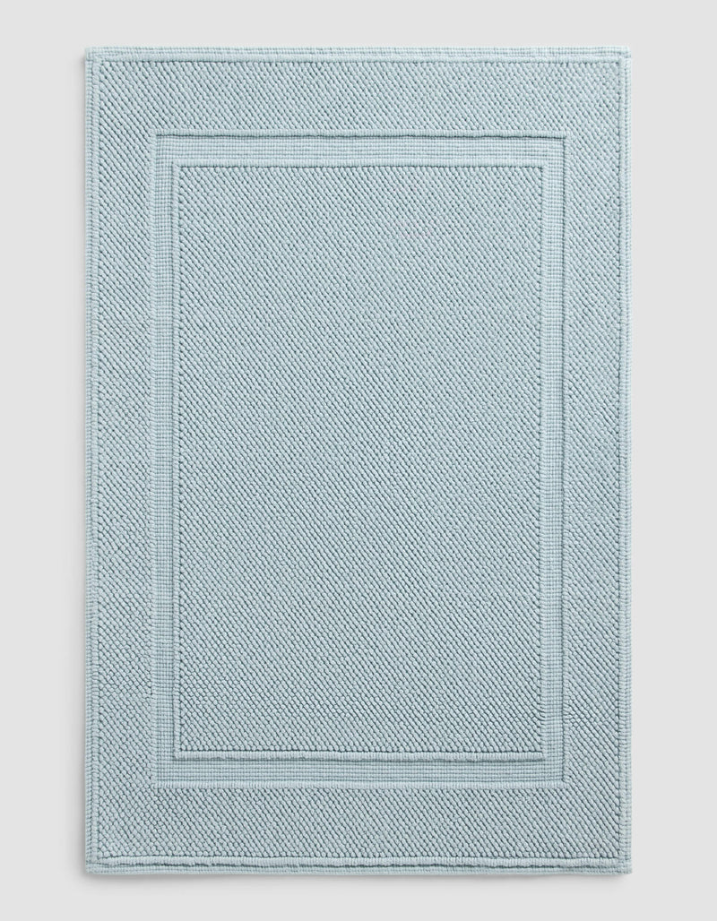The Cozy Earth Classic Bath Mat features a rectangular shape in light blue with a textured surface and double border design, where two rectangles elegantly frame the center for a simple, refined look.