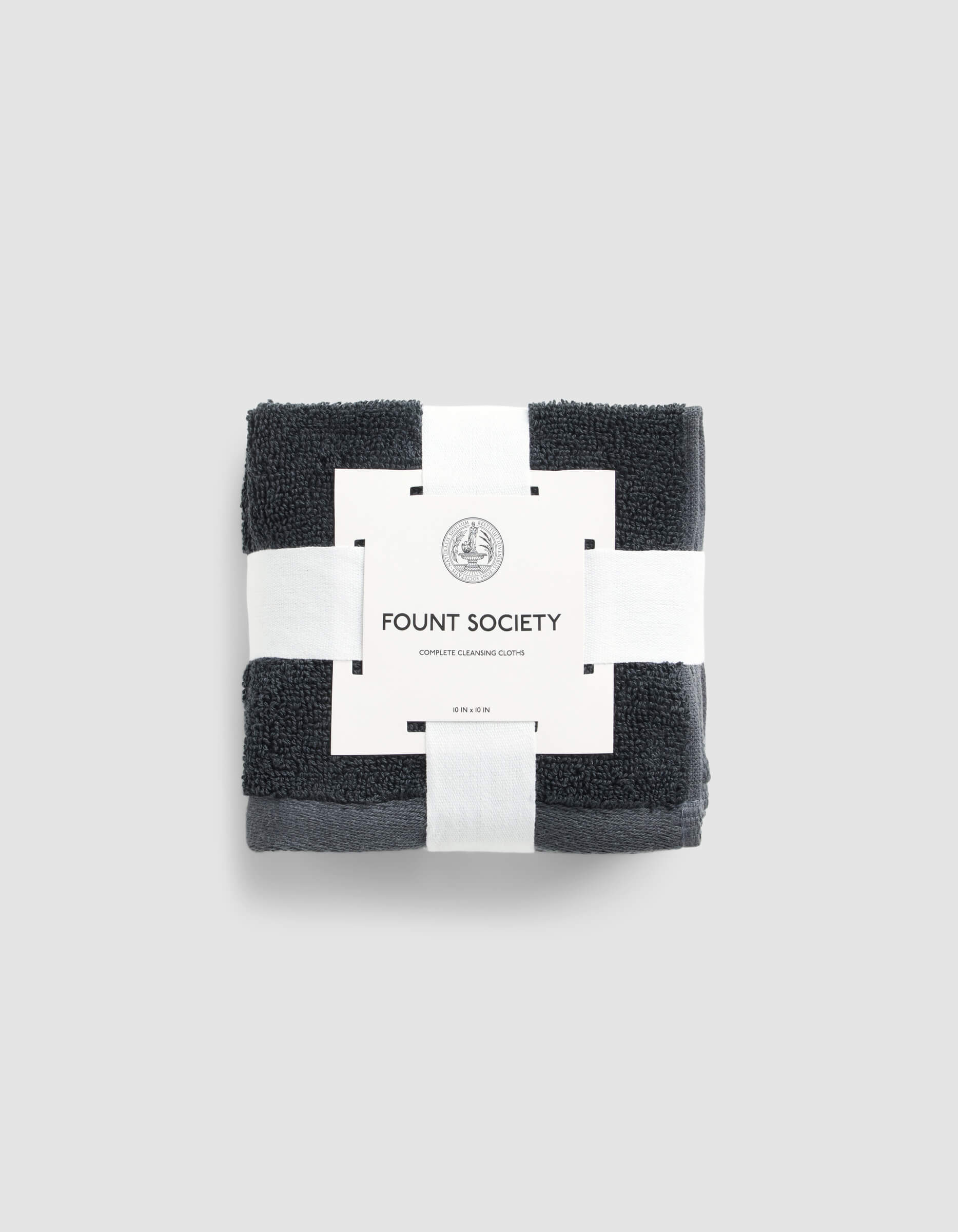 A set of dark gray Complete Cleansing Cloths by Cozy Earth, neatly folded and wrapped with a white paper band, displayed on a light gray background.