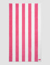 The Cozy Earth Seaside Resort Towel features alternating vertical pink and white stripes on a plain background, with a small pink tag displaying white text in one corner.|Color:Punch Stripe