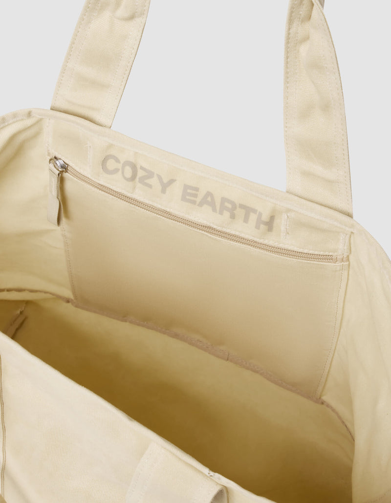 Open Waxed Canvas Tote by Cozy Earth with the brand logo printed above an interior zippered pocket, displaying a roomy interior and sturdy handles against a plain light background.