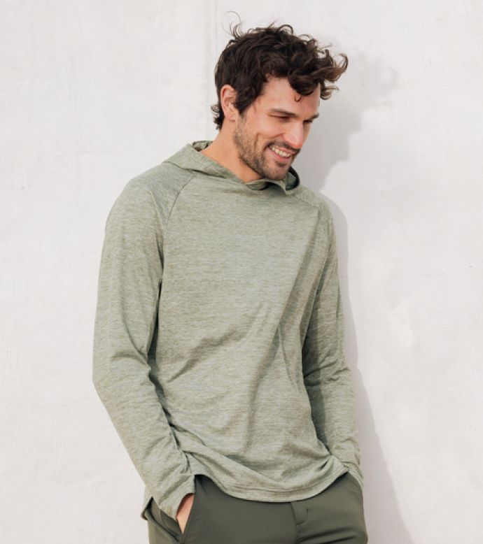 A man wears Cozy Earth Lightweight Performance Hoodie in Heather Olive in front of a white background