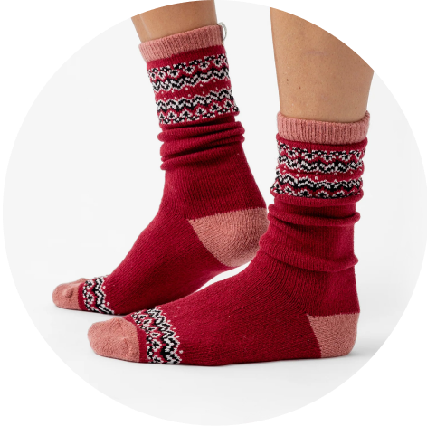 A person wearing Cozy Earth Fair Isle Plush Lounge Socks in Garnet is pictured from the calf down.
