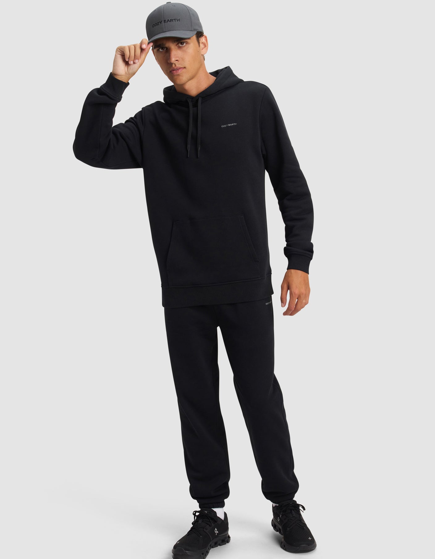 A man wears Cozy Earth Cityscape 2.0 Hoodie and Sweatpants in black in front of a white background
