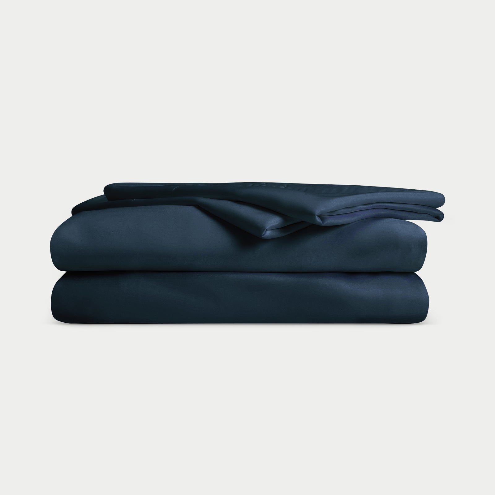 A neatly folded Cozy Earth Bamboo Sheet Set - Overstock in dark blue, including bed sheets and pillowcases, stacked on a plain white background. 